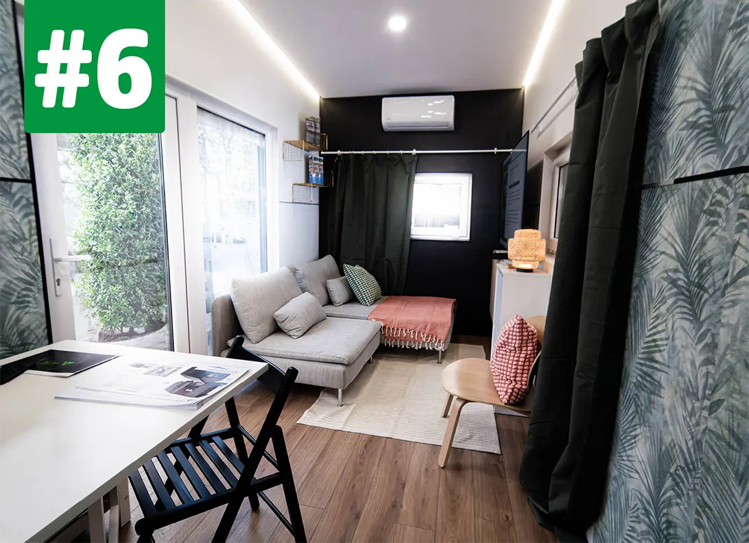 Blick in den Innenraum Wohnbereich eines Tiny House mit Schreibtisch, Stühlen und Ecksofa