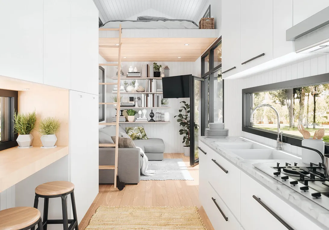 Blick in den Innenraum eines Tiny House mit Küchenzeile, Wohnbereich mit Sofa und Schlafgelegenheit auf zweiter Ebene