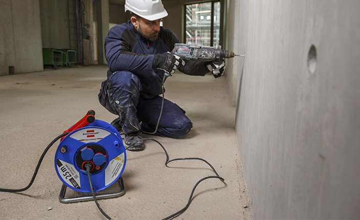 Ein Mann bohrt mit einem Bosch bohrer in eine Wand