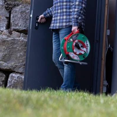 Jemand trägt eine Kabeltrommel von Brennenstuhl nach draußen