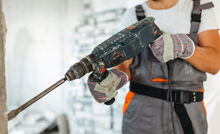Handwerker setzt einen Schlagbohrer an die Wand