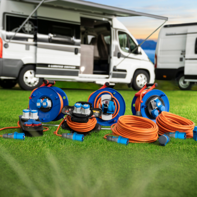 Stromkabel liegen auf einem Rasen vor Campern