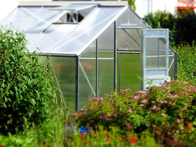 Glasgewächshaus in einem blühenden Garten.