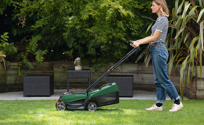 Frau mäht mit einem Bosch Rasenmäher den Rasen