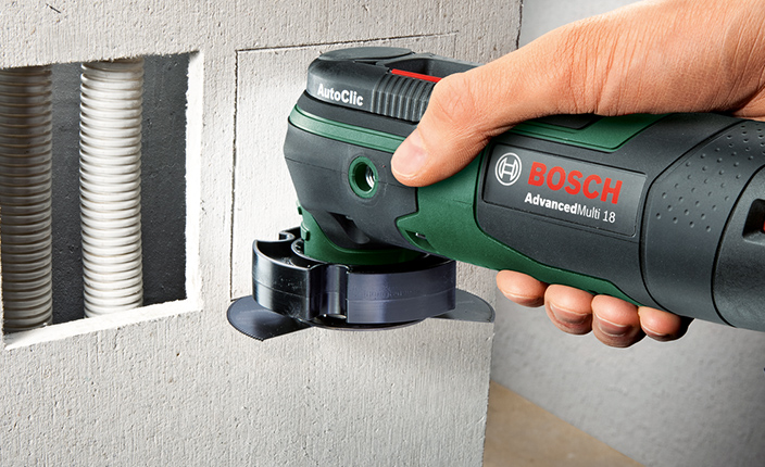 Jemand schneidet ein loch in eine Rigips Wand mit einem Bosch Werkzeug