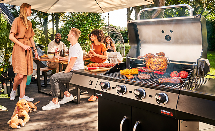Fünf Leute die ein Grillfest feiern mit einem Grill von Char-Broil im Vordergrund