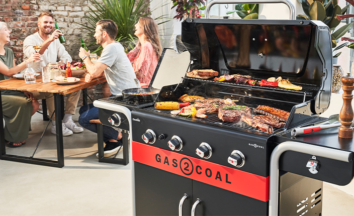 Vier Menschen die ein Grillfest feiern mit einem großen Char-Broil Grill im Vordergrund