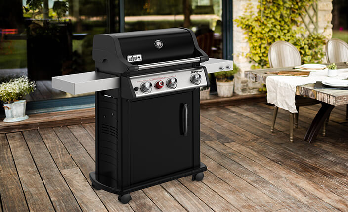 Ein Gasgrill auf einer Terrasse neben einem Esstisch