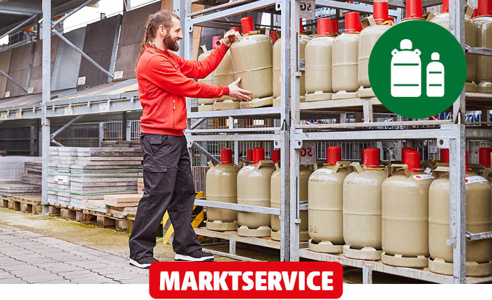 Ein Baumarktmitarbeiter stellt eine Gasflasche in einen Baumarktregal.