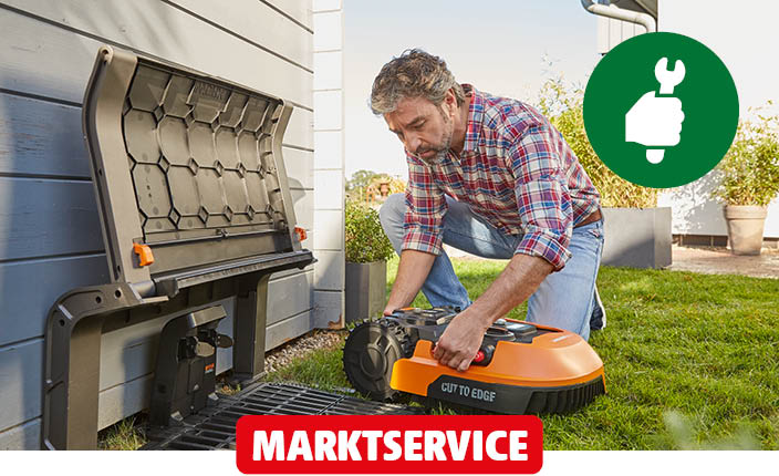 Ein Mann installiert einen Mähroboter in seinem Garten.
