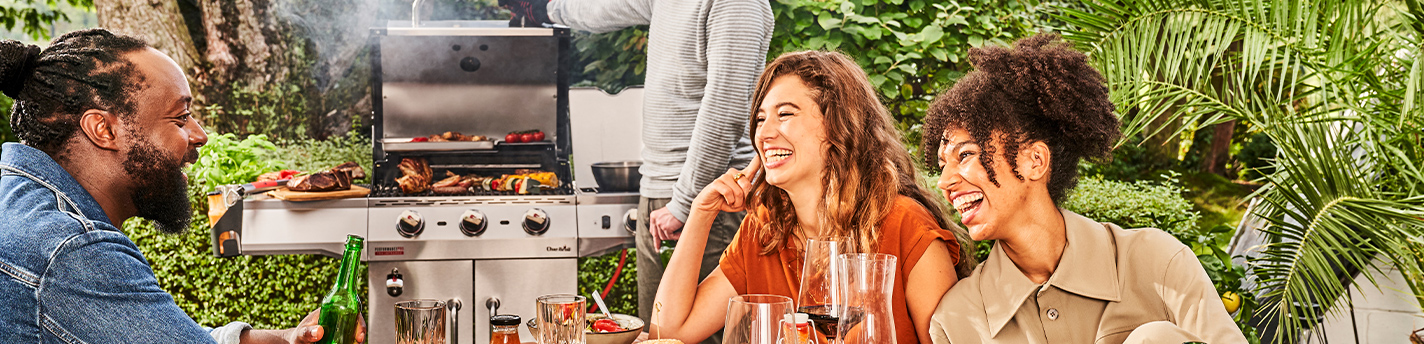 Vier Leute habenspaß bei einem Grillfest mit einem Grill im Hintergrund von Char-Broil