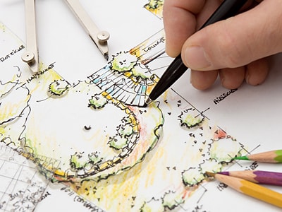 Eine Hand, die einen Plan von einem Bewässerungssystem für einen Garten zeichnet