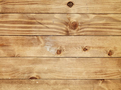 Nahaufnahme einer Holzoberfläche aus horizontal verlegten, naturbelassenen Holzbrettern mit sichtbarer Maserung und Astlöchern.