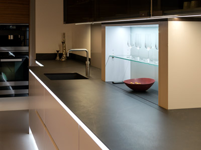 Eine stilvolle Einbauküche mit indirekter LED-Möbelbeleuchtung an Arbeitsplatte und Vitrine mit Gläsern