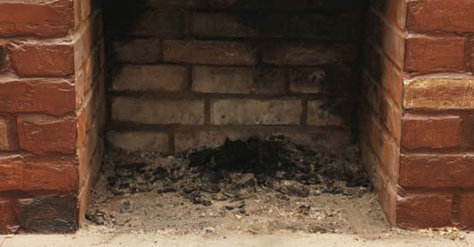 Ein leerer, gemauerter Kamin mit Ascheresten