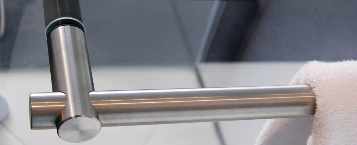 Ein moderner Handtuchhalter aus Edelstahl ist ohne Bohren an einer Glaswand befestigt und hält ein weiches Handtuch