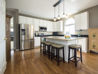 Moderne Küche mit Kücheninsel, Hockern und Edelstahlgeräten.