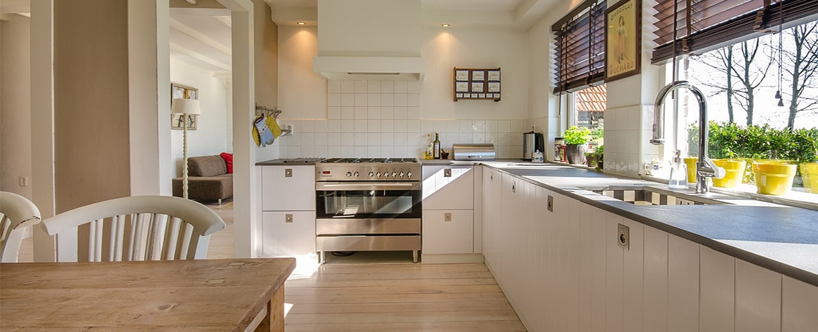 Helle Wohnküche mit großem Herd, Spüle und Esstisch.