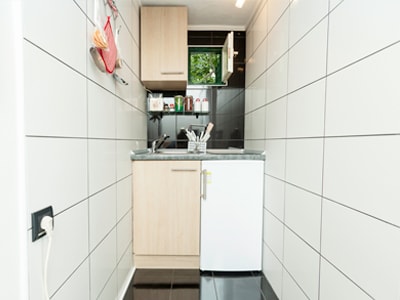 Schmale Miniküche mit Spüle, Unterschrank und kleinem Kühlschrank.