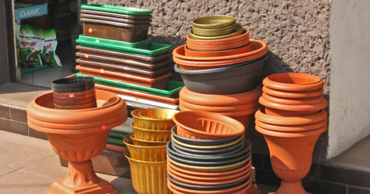 Eine große Auswahl an Pflanzgefäßen in verschiedenen Formen und Farben ist vor einem Geschäft gestapelt