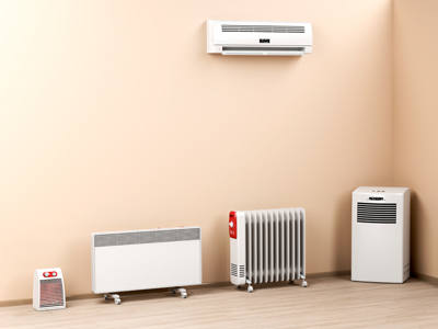 In einem Raum stehen fünf verschiedene Heizgeräte nebeneinander, darunter ein Radiator, ein Konvektor und eine Klimaanlage an der Wand.