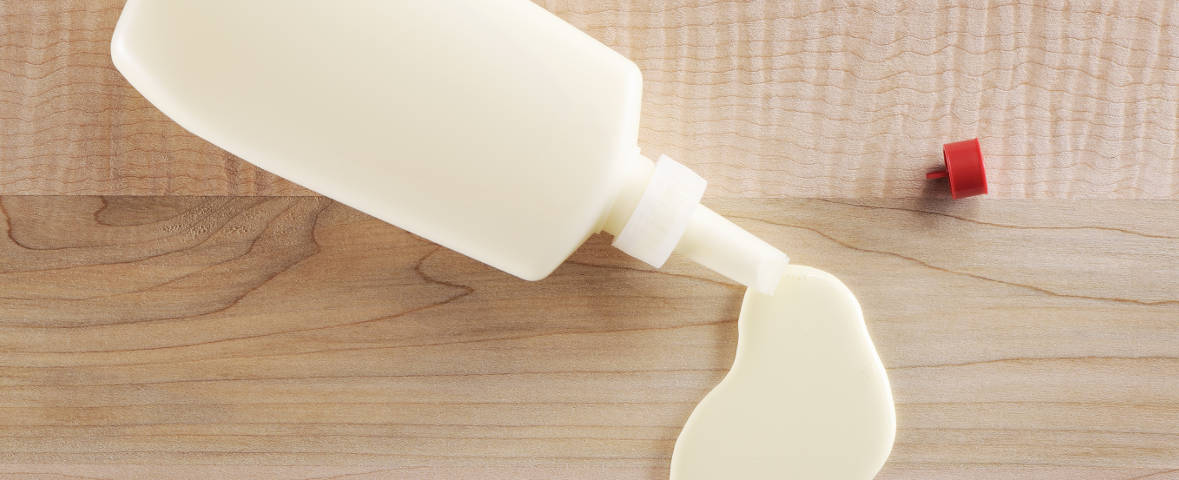 Geöffnete Flasche Holzleim auf einer Holzoberfläche.